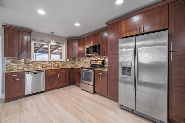 kitchen featuring decorative light fixtures, decorative backsplash, light stone countertops, and appliances with stainless steel finishes