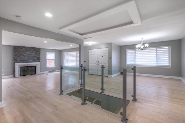 workout room featuring a stone fireplace, light wood-type flooring, and a chandelier