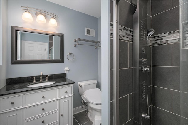 bathroom with tile patterned floors, vanity, a shower with shower door, and toilet