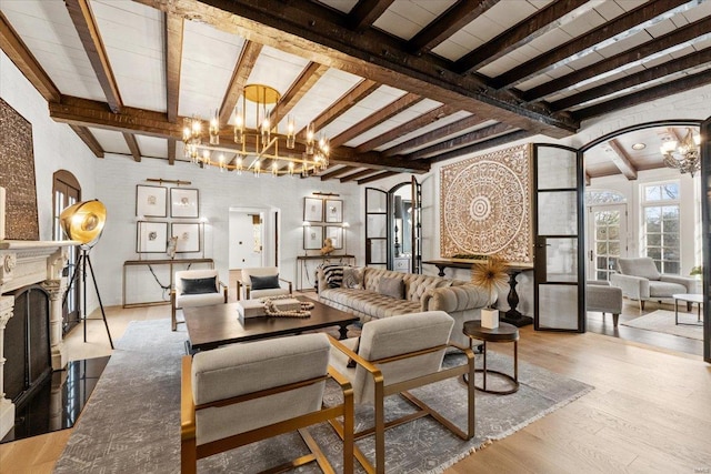 living room featuring an inviting chandelier, beam ceiling, and light wood-type flooring