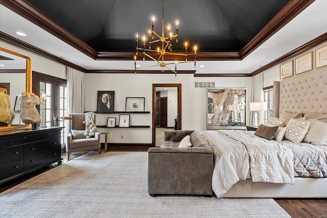 bedroom with a raised ceiling, ornamental molding, hardwood / wood-style floors, and french doors