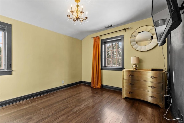 unfurnished bedroom with lofted ceiling, dark hardwood / wood-style floors, and an inviting chandelier