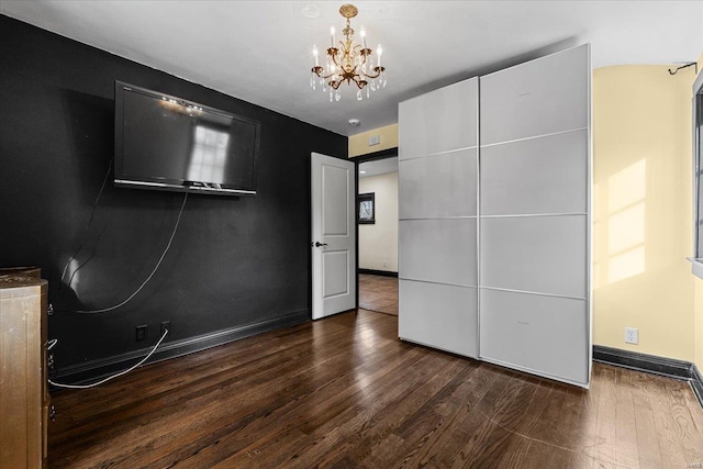 unfurnished bedroom featuring dark hardwood / wood-style floors and a chandelier