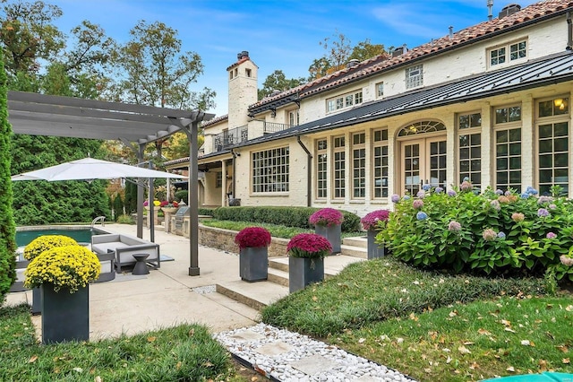 rear view of property featuring a pergola and a patio