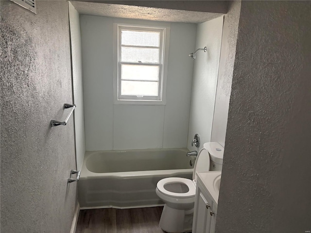 full bathroom featuring wood-type flooring, a textured ceiling, toilet, vanity, and shower / bathtub combination