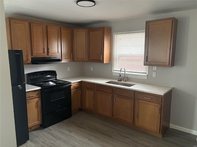 kitchen with sink, ventilation hood, light hardwood / wood-style floors, and black appliances