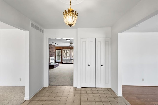 interior space featuring a chandelier, light colored carpet, visible vents, and baseboards