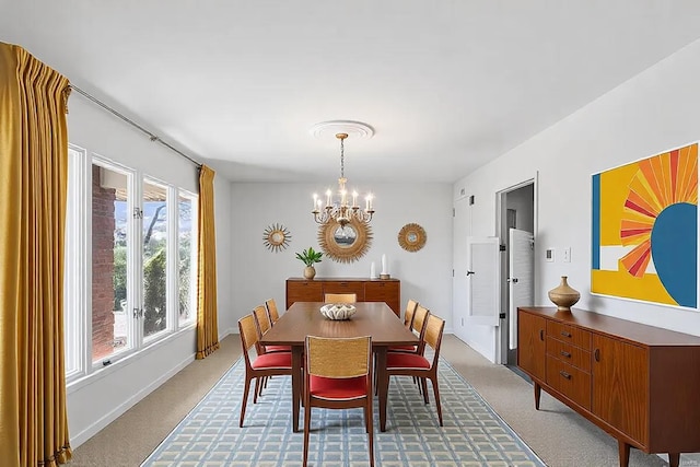 dining space featuring light colored carpet, a notable chandelier, and baseboards