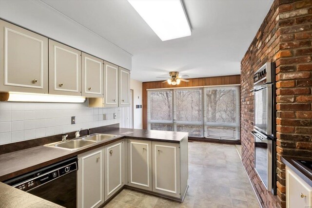 kitchen featuring dark countertops, a ceiling fan, a sink, dishwasher, and a peninsula