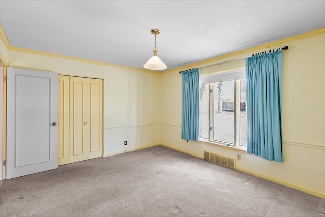 unfurnished bedroom with carpet, a closet, visible vents, and crown molding