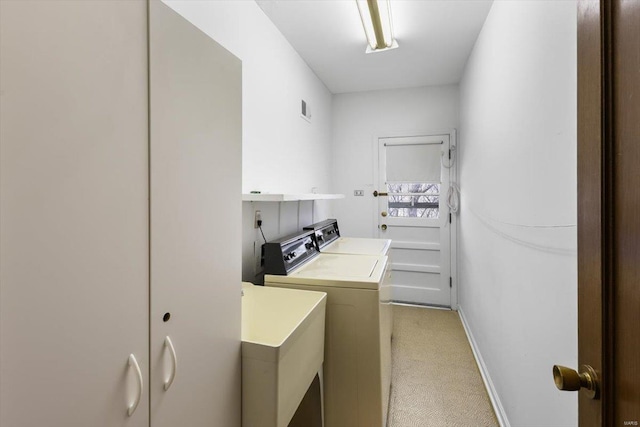 clothes washing area featuring light carpet, laundry area, visible vents, independent washer and dryer, and a sink