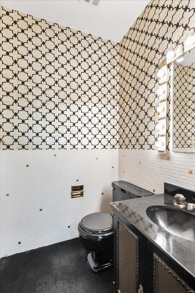 bathroom with toilet, visible vents, vanity, and tile walls