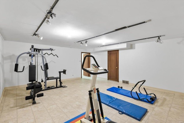 exercise room with rail lighting, visible vents, and baseboards