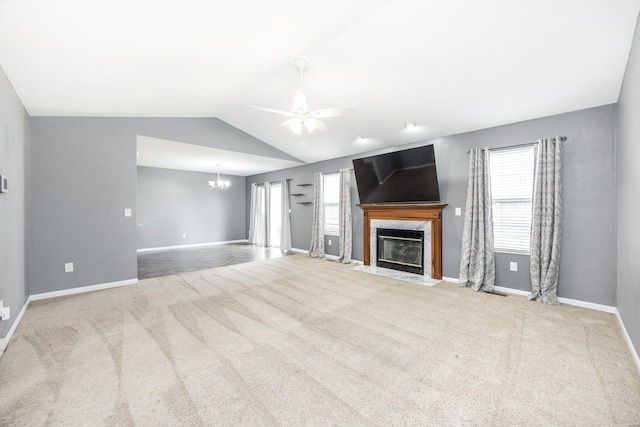 unfurnished living room with a fireplace, ceiling fan with notable chandelier, a healthy amount of sunlight, and vaulted ceiling