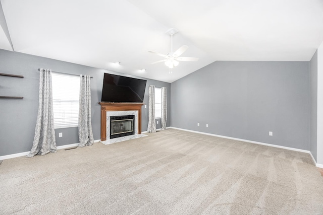 unfurnished living room featuring ceiling fan, a high end fireplace, a healthy amount of sunlight, and lofted ceiling