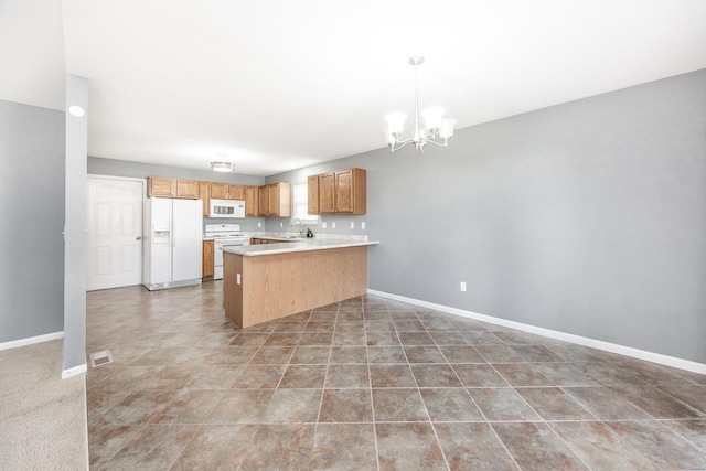 kitchen with kitchen peninsula, white appliances, sink, decorative light fixtures, and an inviting chandelier