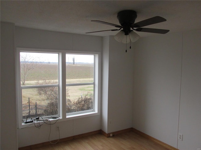 empty room featuring ceiling fan, light hardwood / wood-style floors, and a rural view