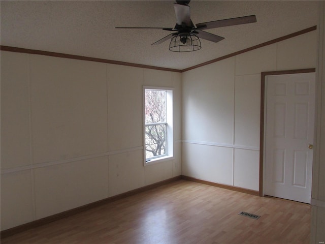 spare room with a textured ceiling, light wood-type flooring, ceiling fan, and crown molding