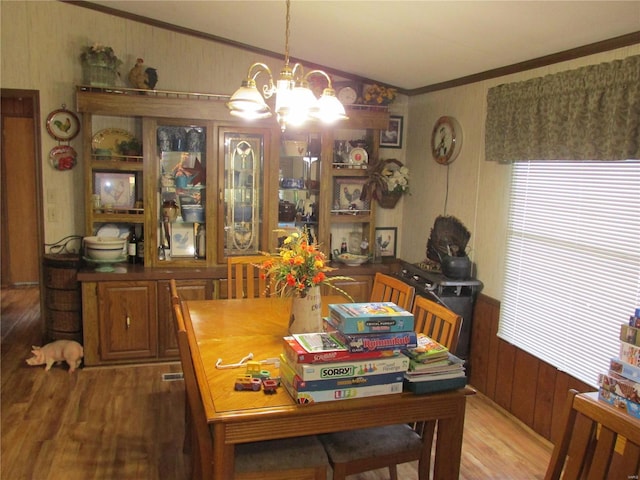 dining space with a notable chandelier, ornamental molding, hardwood / wood-style floors, and wooden walls