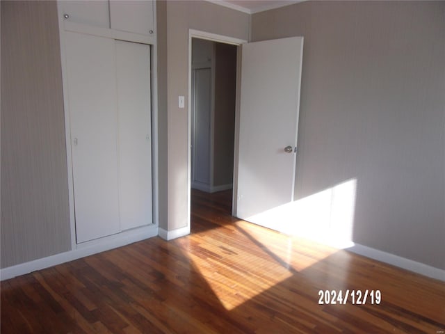 unfurnished bedroom featuring dark hardwood / wood-style flooring and a closet