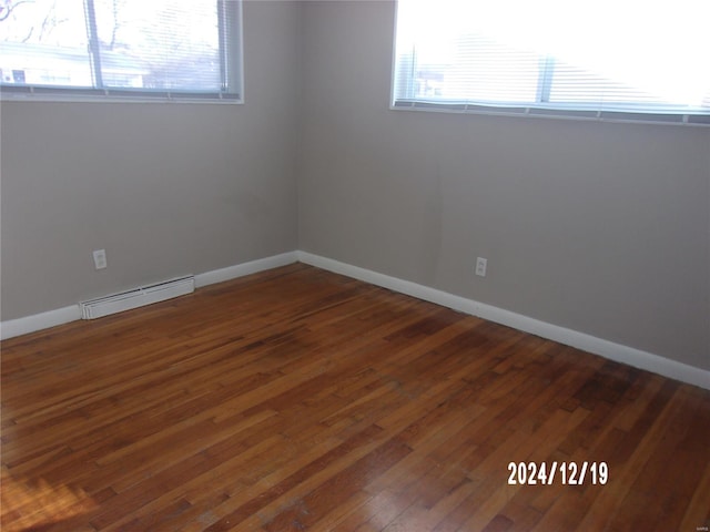 spare room featuring baseboard heating and dark wood-type flooring