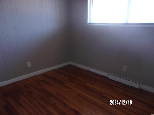 unfurnished room featuring dark hardwood / wood-style flooring and a baseboard radiator