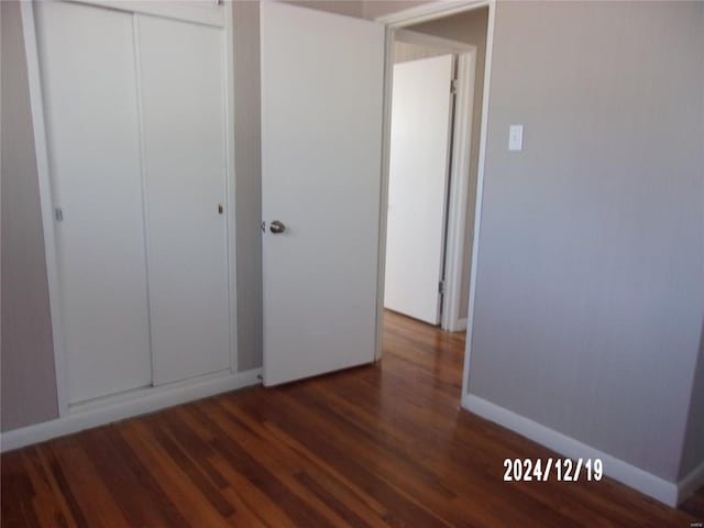 unfurnished bedroom featuring dark wood-type flooring and a closet