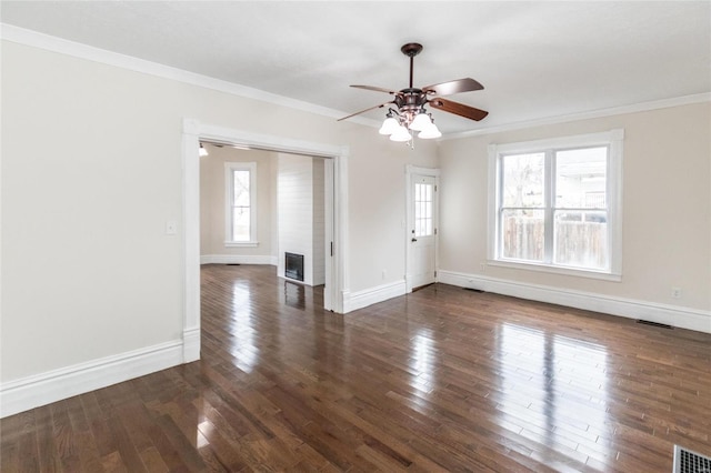 spare room with a fireplace, dark hardwood / wood-style floors, ceiling fan, and ornamental molding