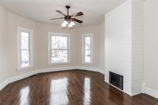 unfurnished living room featuring ceiling fan, a large fireplace, and dark wood-type flooring