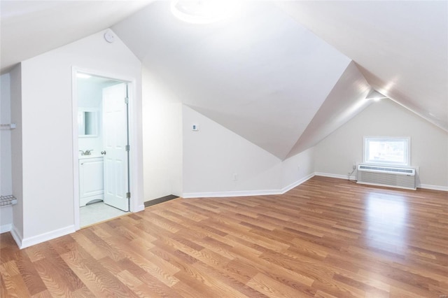 bonus room featuring light hardwood / wood-style flooring, vaulted ceiling, and a wall unit AC