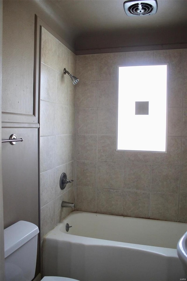 bathroom with tiled shower / bath combo and toilet