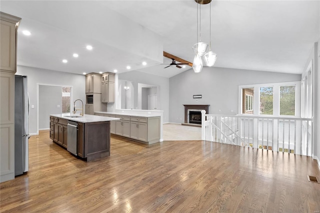 kitchen with appliances with stainless steel finishes, light wood-type flooring, sink, a center island with sink, and gray cabinets