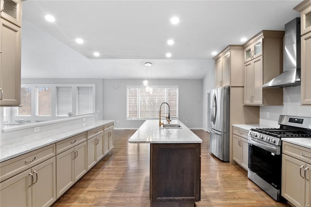 kitchen featuring sink, wall chimney exhaust hood, hanging light fixtures, stainless steel appliances, and an island with sink