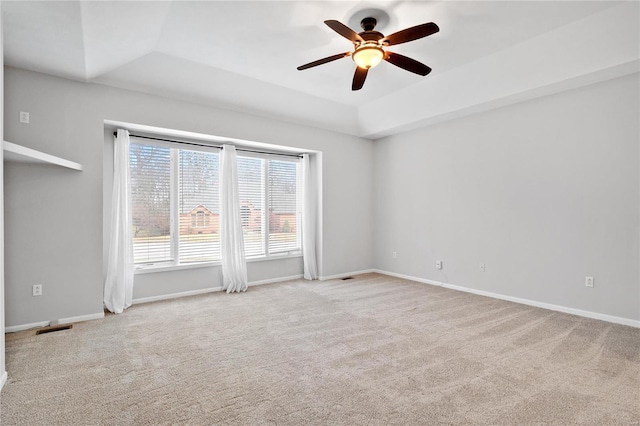 carpeted spare room with a tray ceiling and ceiling fan