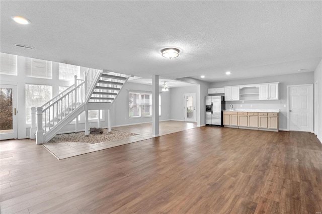 unfurnished living room with ceiling fan, wood-type flooring, and a textured ceiling