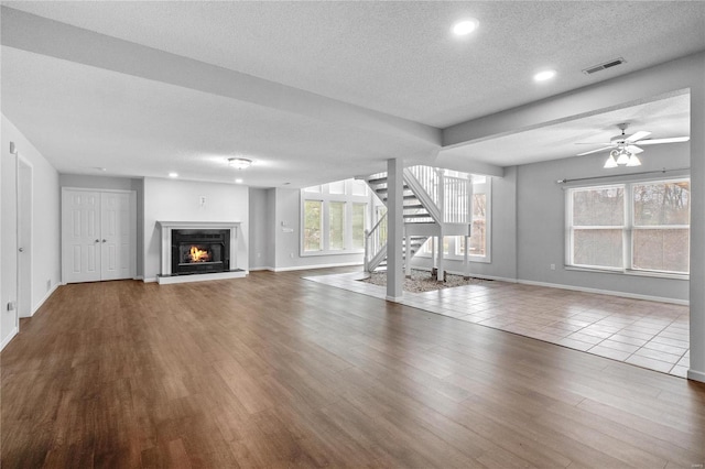 unfurnished living room with ceiling fan, a textured ceiling, and hardwood / wood-style flooring