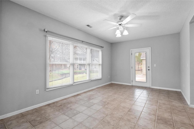 tiled spare room featuring a textured ceiling and ceiling fan