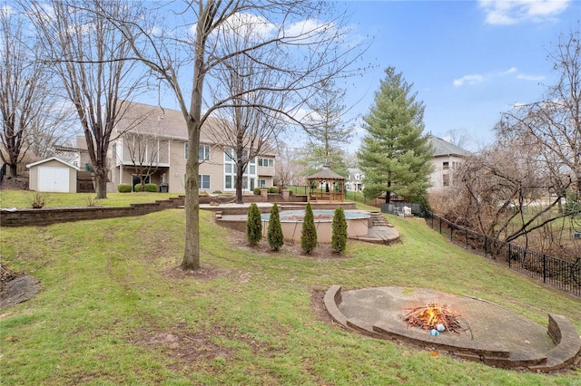 view of yard featuring a gazebo, a storage unit, a fire pit, and a pool