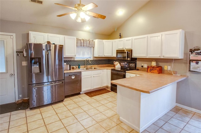 kitchen featuring sink, light tile patterned flooring, kitchen peninsula, white cabinets, and appliances with stainless steel finishes