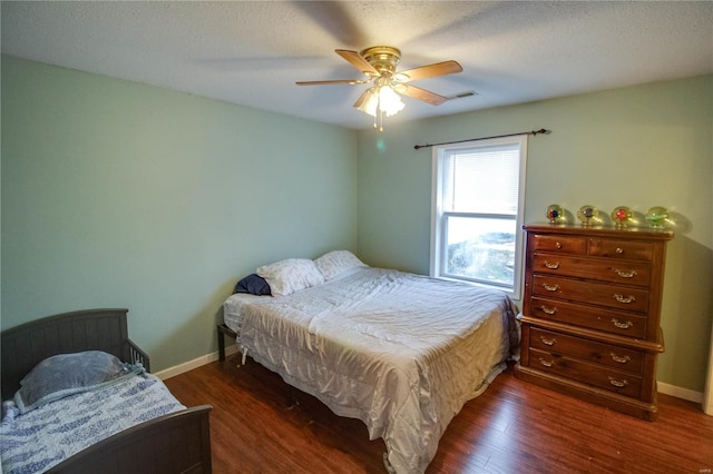 bedroom featuring ceiling fan, dark hardwood / wood-style flooring, and a textured ceiling