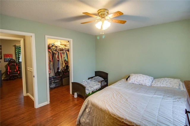 bedroom with ceiling fan, wood-type flooring, a walk in closet, and a closet