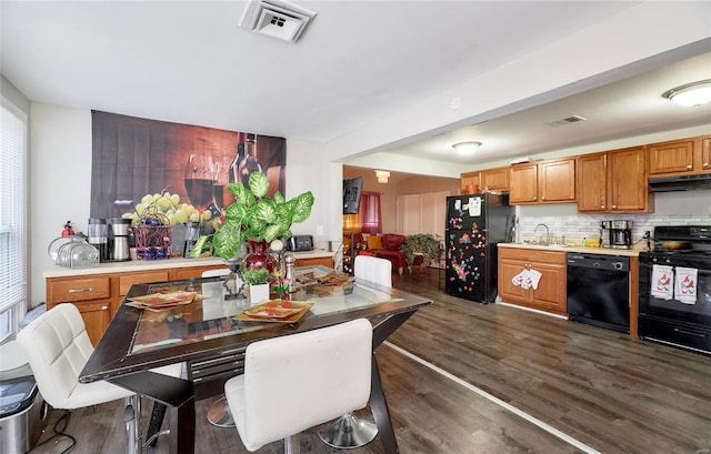 kitchen with dark hardwood / wood-style flooring, decorative backsplash, sink, and black appliances