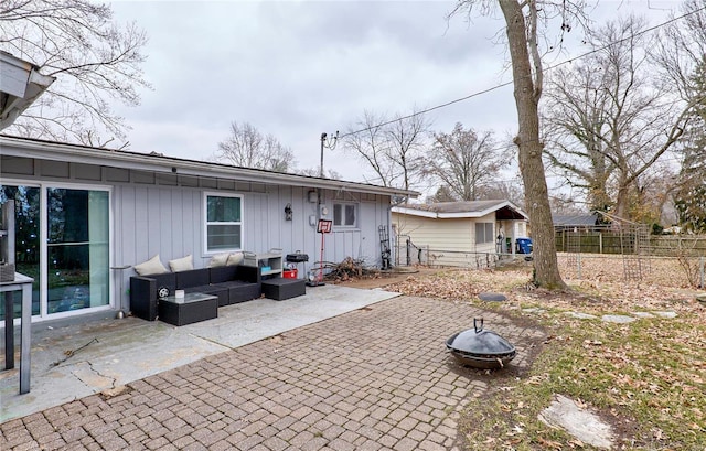 rear view of property featuring a patio and an outdoor living space with a fire pit