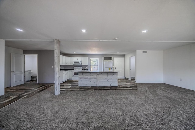 kitchen with white cabinets, a kitchen island, dark carpet, and white appliances