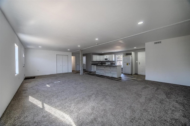 unfurnished living room with dark colored carpet