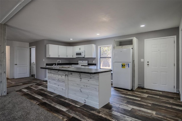 kitchen with white appliances, sink, dark hardwood / wood-style floors, white cabinetry, and an island with sink