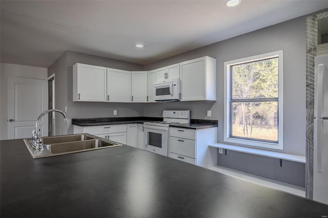 kitchen featuring plenty of natural light, white cabinetry, sink, and white appliances