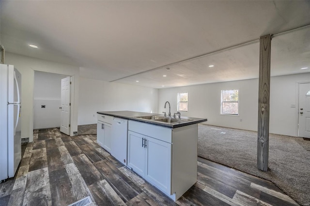 kitchen featuring dark hardwood / wood-style flooring, white appliances, a kitchen island with sink, sink, and white cabinets