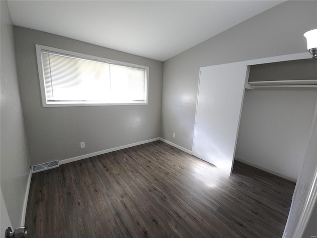 unfurnished bedroom with lofted ceiling, dark wood-type flooring, and a closet