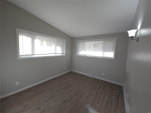 spare room featuring dark hardwood / wood-style flooring and vaulted ceiling